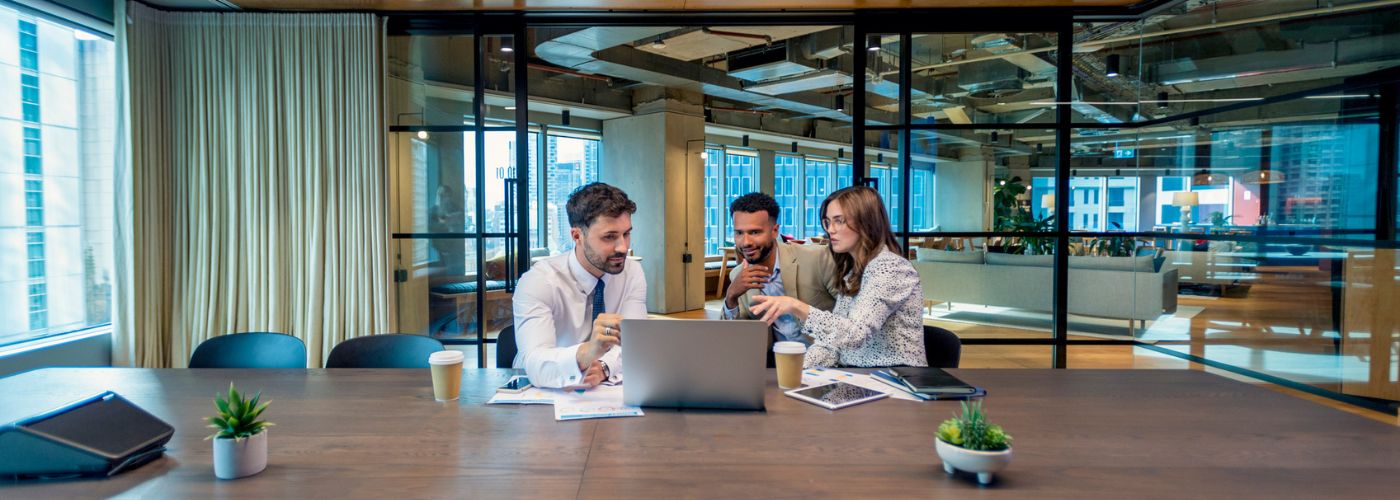 Couple meeting with insurance agent in front of laptop in an office.