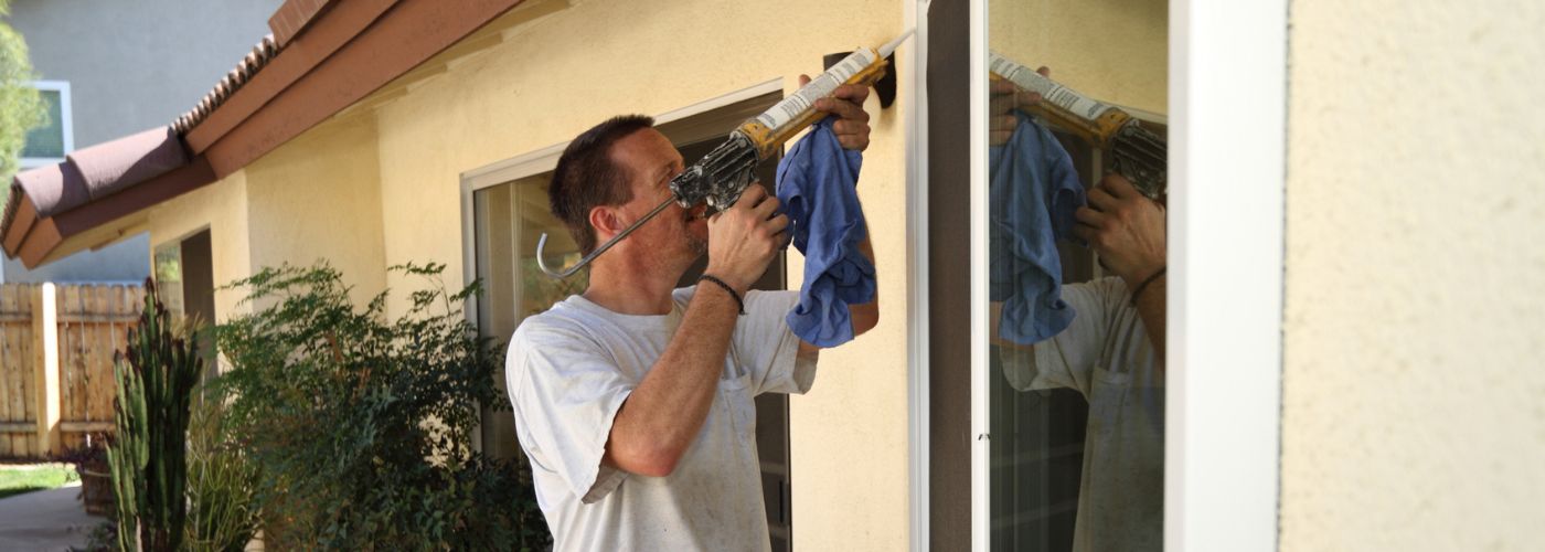 Man caulking an outside window.